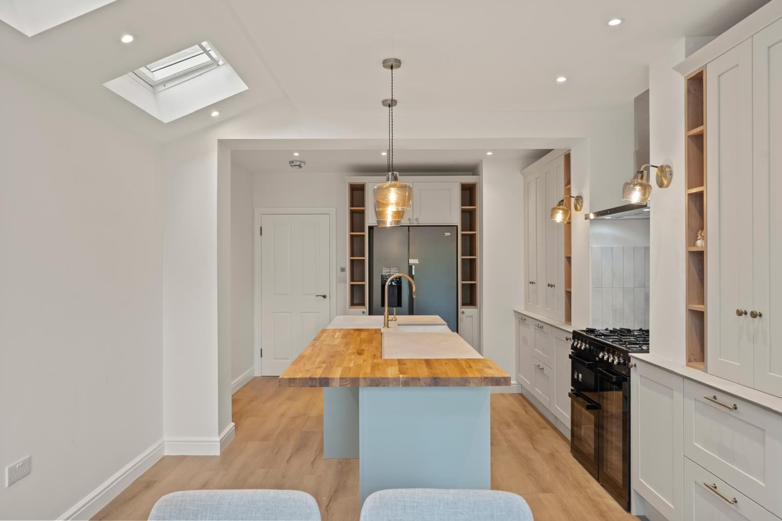 Light grey shaker kitchen with a timber topped island and rooflights