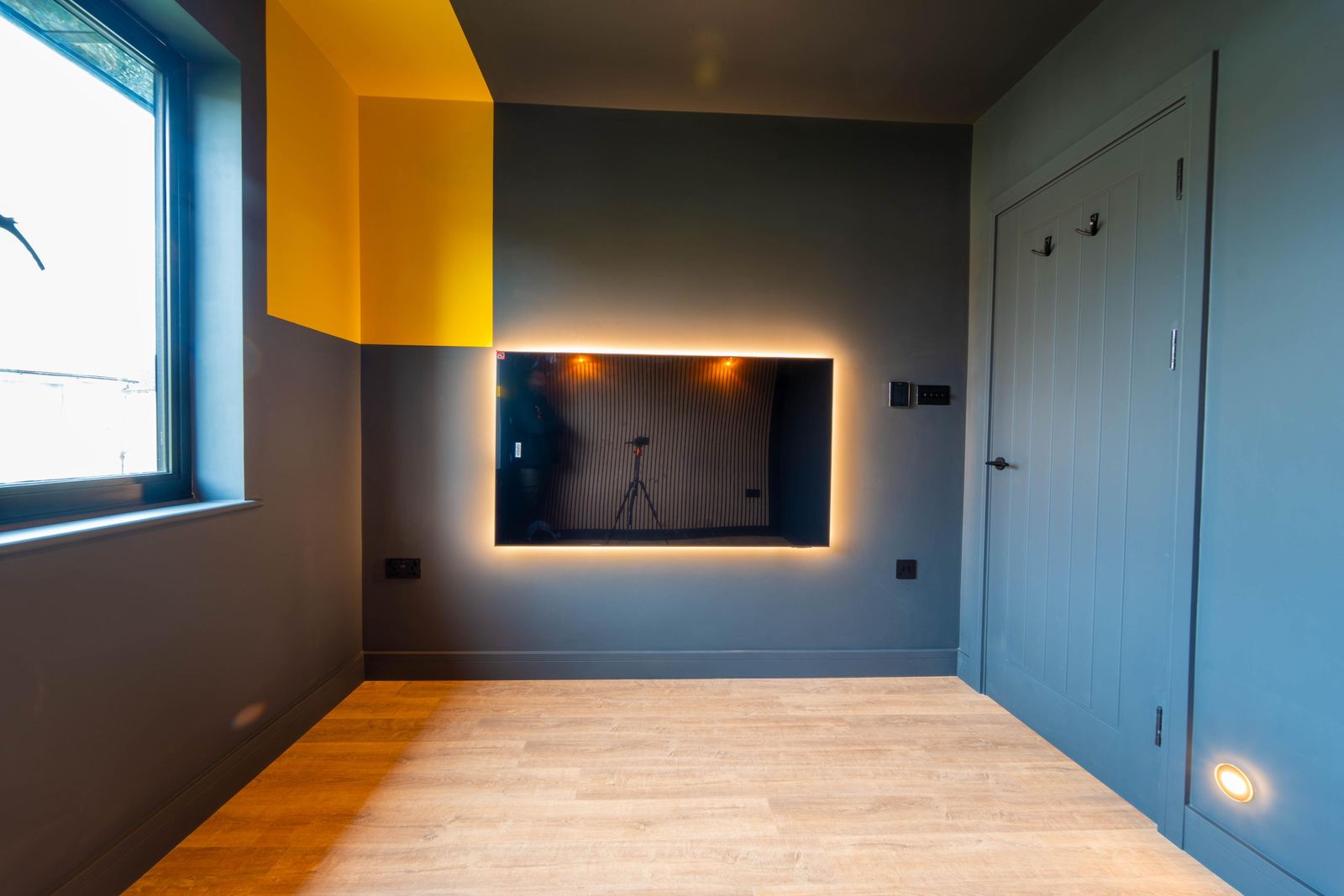 Room with a lit wall panel, yellow and blue walls and a panelled door