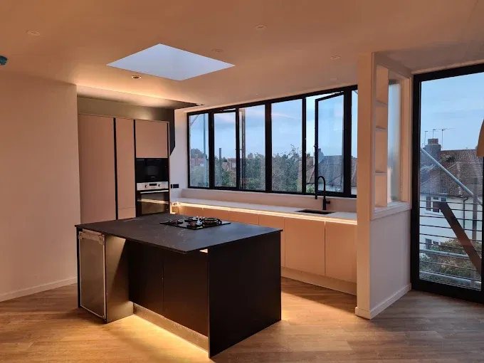 Kitchen with a dark island, rooflight and floor to ceiling glazing