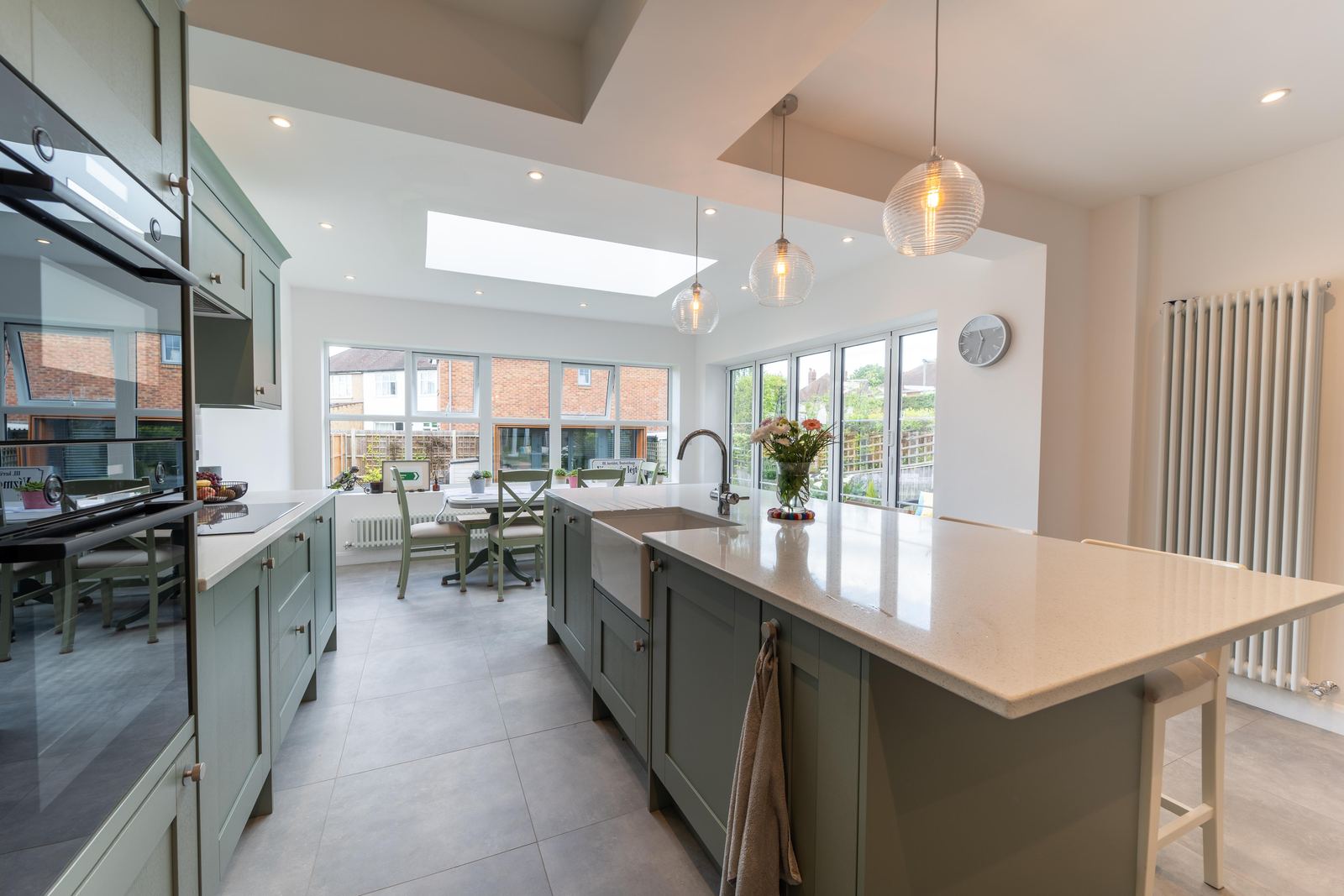 Sage green kitchen with island, dining space and a roof lantern