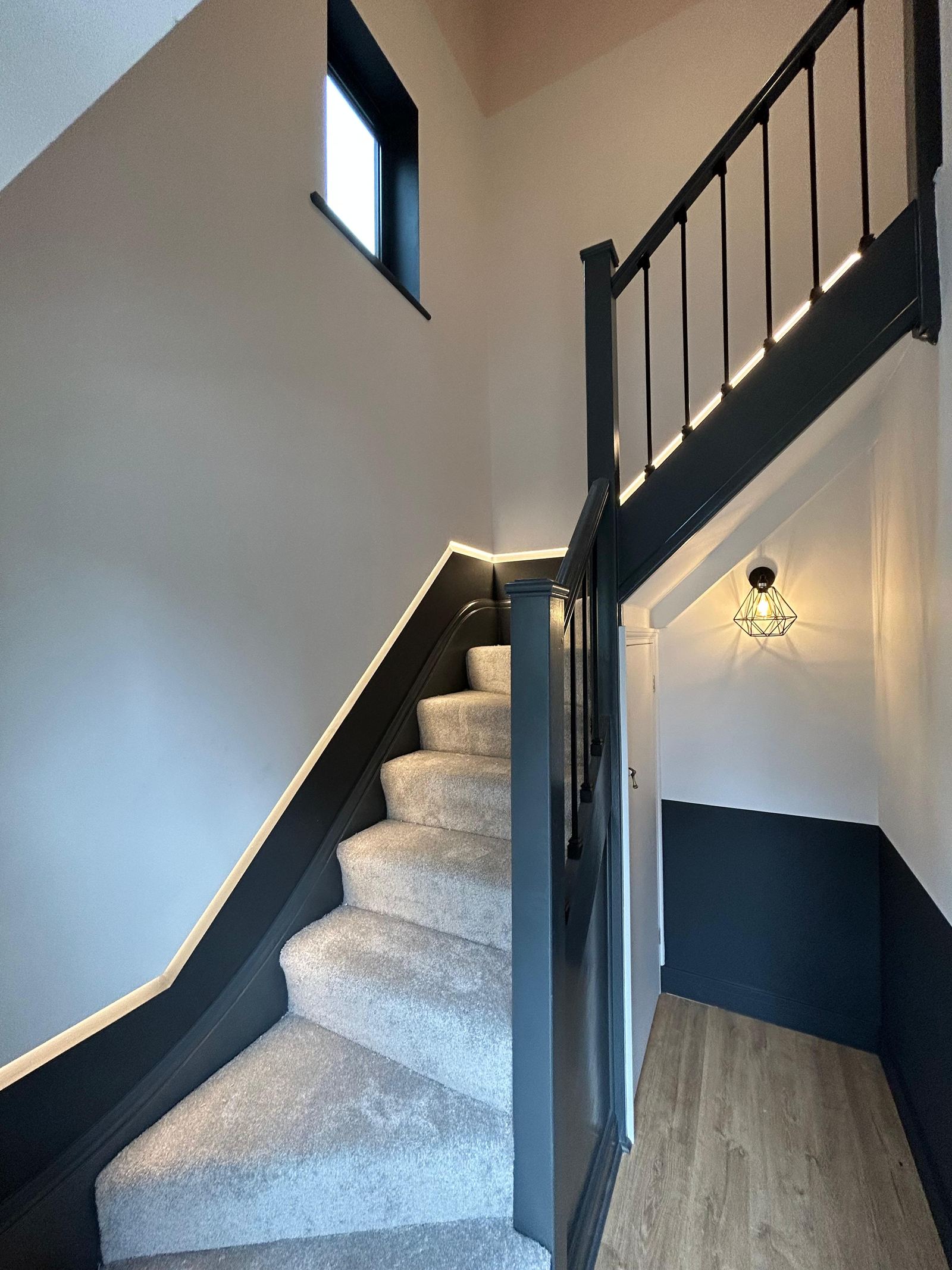 Staircase with dark painted handrail, carpet runner and lighting